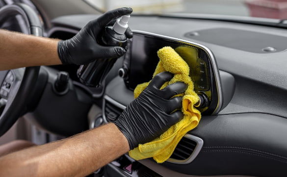 close up of employee detailing the dashboard of a vehicle
