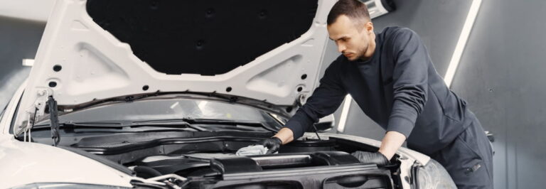 man cleaning engine in auto shop