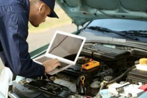 Mechanic Using Computer Diagnostics While Repairing Car